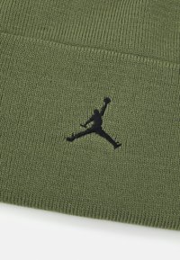 Zelena pletena kapa s teksturiranom površinom i crnim izvezenim Jumpman logotipom istaknutim na prednjoj strani.