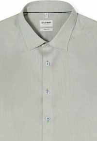 Chemise habillée homme gris clair à manches longues avec col pointu, boutonnée sur le devant, avec étiquette « Olymp Level Five Body Fit » à l'intérieur du col.