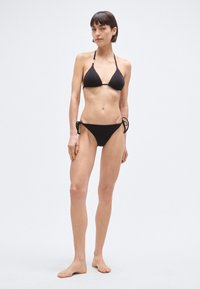 Črni bikinij z dvokotnim zgornjim delom in spodnjim delom z vezalkami na straneh. Iz gladkega blaga, s preprostim dizajnom in nastavljivimi naramnicami.