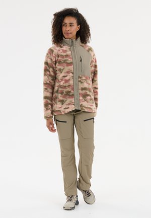 Fleecejacka med rosa, grön och brun camouflage-mönster, dragkedja fram och bröstficka. Kombinerad med beige cargobyxor och vandringsskor.