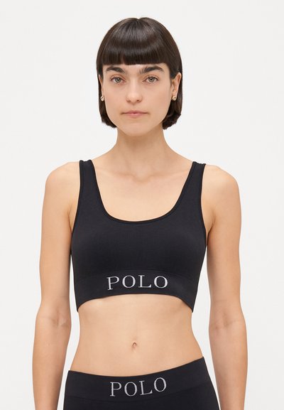 Czarny sportowy stanik z prążkowanej tkaniny, z szerokim pasem, ozdobiony wyszywanym logo "POLO" w kolorze srebrnym. Posiada dekolt w kształcie łódki oraz grube ramiączka.
