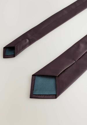 Bordo kravata s teksturiranim površinom; šiljasti krajevi prikazuju kontrastnu plavu unutrašnjost s malim bijelim točkicama. Glatka završna obrada, elegantan dizajn.