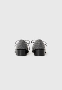 Gray knit fabric lace-up shoes with black chunky heels, shown from the back on a white background.