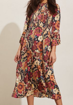 Vestido midi floral con mangas largas, que presenta un fondo oscuro y patrones vibrantes en naranja, rosa y blanco. Diseño de mangas acampanadas.