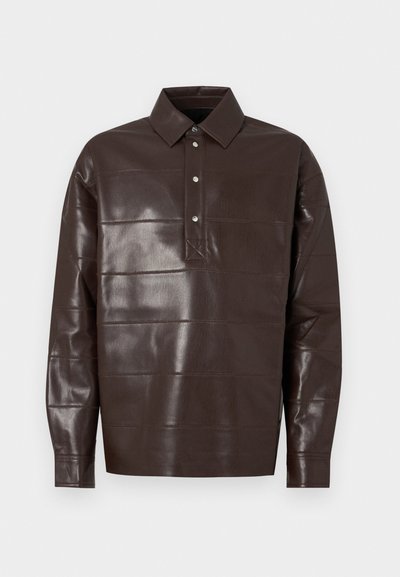 Sötétbarna bőr hosszú ujjú ing, hegyes gallérral és három fémbottonnal ellátott elülső gombolással.