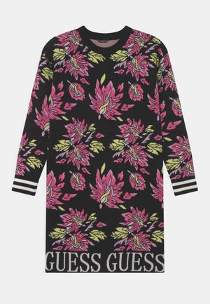 Czarna sukienka sweterkowa z długim rękawem, z różowymi i żółtymi kwiatowymi wzorami, paskowanymi mankietami oraz napisem "GUESS" na dolnym brzegu.