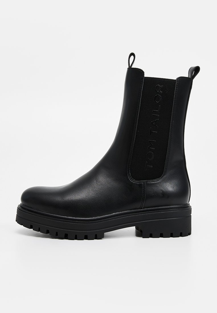 Bottine noire en cuir lisse avec panneaux élastiques sur les côtés et logo, dotée d'une semelle en caoutchouc texturée et épaisse.