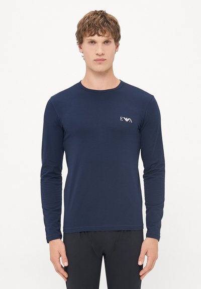 Mørkeblå langermet skjorte med en tettsittende design, laget av smidig stoff. Har en liten logo på brystet og en rund halslinning.