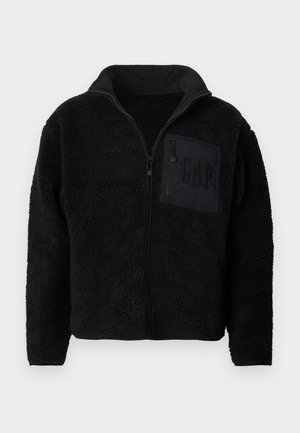 Schwarze Fleece-Jacke zum Zippen mit strukturiertem Stoff und einer Brusttasche mit Reißverschluss, die ein dezentes "GAP"-Logo trägt.