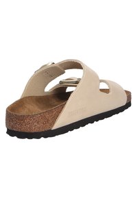 Light beige Birkenstock sandal with dual straps, cork footbed, and textured rubber outsole. Features adjustable metal buckles and cutouts.