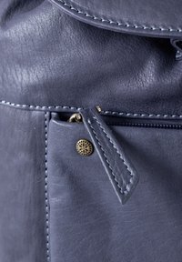 Leather bag in dark blue with a textured surface, featuring a zippered pocket and gold-tone hardware detail. Stitching in a lighter blue.