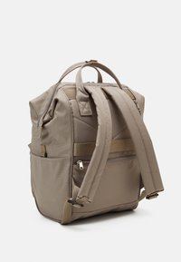 Beige rugzak met gewatteerde schouderbanden, bovenhandvatten, zijvakjes en een ritsvak op een witte achtergrond.