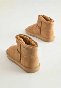 Bruine suède enkelboots met faux bontvoering, ronde neus en rubberen zool. Zijkant detail, een korte hoogte en zachte textuur.