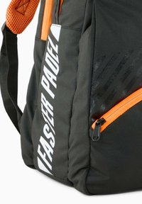 Czarny sportowy plecak z pomarańczowym zamkiem błyskawicznym, z białym logo i teksturowanymi akcentami. Trwały materiał z wyściełanymi paskami na ramiona.