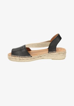 Black leather espadrille sandal with a closed toe, elastic strap, and a woven jute sole. Smooth texture and minimalistic design.
