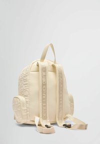 Zaino beige con un design del logo testurizzato. Presenta spallacci imbottiti e regolabili, un compartimento centrale e una tasca laterale. Materiale liscio.