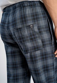 Geblokte loungebroek in blauw, grijs en zwart. Elastische tailleband, zijzakken en een achterzak met een logo label. Zachte stoftextuur.