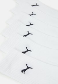 White athletic socks with ribbed texture, featuring a black logo on each sock. Six pairs displayed in a stacked arrangement.