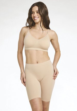 Beige seamless bra with adjustable straps and matching high-waisted shorts. Smooth texture and body-hugging design.