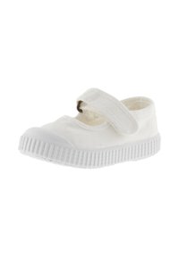 Zapato de lona blanco con punta redondeada, correa de velcro y suela de goma texturizada con ranuras para un mejor agarre. Diseño simple y minimalista.
