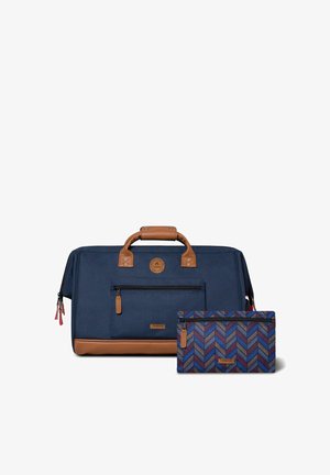 Sac de voyage en toile bleu marine avec des accents en cuir marron, une poche zippée à l'avant et une pochette assortie à motif en chevrons.