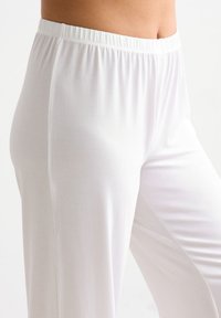 Weiße Hose mit elastischem Bund aus einem weichen, leichtgewichtigen Stoff mit glatter Textur und lässiger Passform, die bis zum Knöchel reicht.