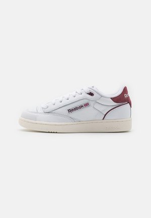 Hvid Reebok lavtop sneaker med vinrød hællap, beige sål og Reebok-logo med britisk flag på sidepanelet.
