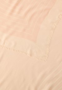 Heledat kui riie, millel on õrn narmastega ääris ja geomeetriline muster, kus kordub sõna "BOSS".