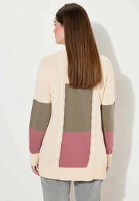 Sweter kardigan z kremową bazą, z prostokątnymi blokami kolorów w oliwkowej zieleni i mauve, z detalami w splocie warkoczowym na plecach.