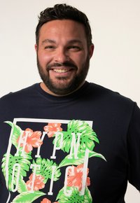 Námořnické tričko s krátkým rukávem s květinovým designem, na němž jsou zelené listy a oranžové květy, s tištěným textem "HYPNOTIC" v bílé barvě.