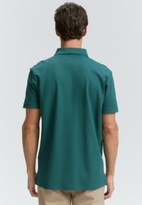 Turkisbla polo shirt, korte ærmer, blødt stof, klassisk krave, rene linjer og et ensfarvet bagdesign. Velegnet til fritidsbrug.