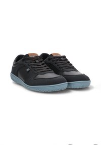 Zapatillas negras con parte superior de piel suave y textil, suela de goma azul y acento marrón en la lengüeta. Cuenta con cordones tradicionales.