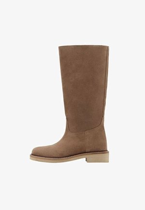 Bota de ante marrón hasta la rodilla con un acabado suave, punta redonda, suela plana y detalles de costura mínimos para un diseño limpio.