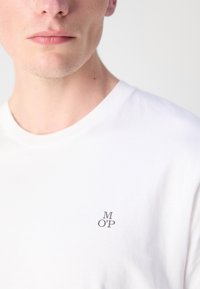 Witte katoen t-shirt met een ronde halslijn en een klein, grijs "M OP" logo op de linkerkant van de borst. Soepele textuur, klassieke pasvorm.