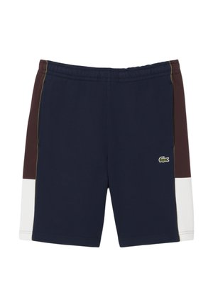 Pantalones cortos deportivos en color marino y marrón con cintura elástica, paneles laterales en blanco contrastante y detalle del logo en verde en la parte inferior izquierda.