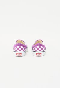 Lila kockás slip-on cipők fehér gumitalpakkal. Vászon anyag és márkás piros címke a sarkán. Minimalista dizájn, fűzők nélkül.