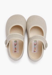 Zapatos Mary Jane de lona beige con punta redondeada, correa ajustable y detalle de botón; el interior presenta un forro texturizado.