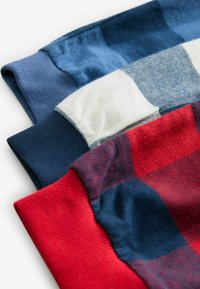 Trois manches en tissu pliées : bleu à côtes, marine avec un patch blanc, et écossais rouge. Texture douce ; divers motifs et textures de couleurs affichés.
