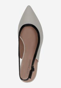 Chaussure à talon slingback à bout pointu en crème avec une bordure noire. Texture lisse, petit talon et une sangle fine à la cheville avec un détail de boucle.