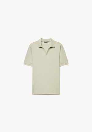 Polo manica corta color beige chiaro con trama a coste e colletto aperto, distesa su sfondo bianco.