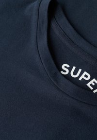 Dunkelblaues Baumwoll-T-Shirt mit Rundhalsausschnitt und einem sichtbaren "SUPER"-Label in weißem Text am inneren Kragen, glatte Textur.