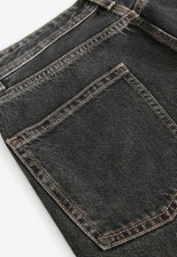 Jeans din denim negru cu o textură ușor estompată, ce prezintă cusături contrastante de culoare portocalie și un buzunar posterior cu un design înclinat pentru clapetă.