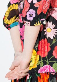 Kolorowa sukienka w kwiaty z dużymi słonecznikami, różami i stokrotkami na czarnym tle, z krótkimi rękawami i zebranym dołem.