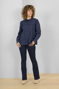 Marineblaue Hemdbluse mit gerafften Stufen, langen Ärmeln und Kragen. Kombiniert mit dunklen Jeans und beigen Stiefeletten auf einer Holzoberfläche.