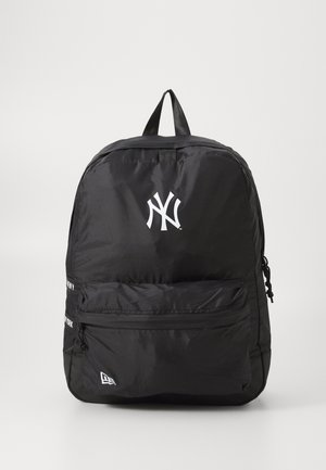 Sac à dos en nylon noir avec une poche zippée à l'avant, arborant un logo des New York Yankees en blanc ainsi que des accents textuels. Texture lisse, forme standard, bretelles réglables.