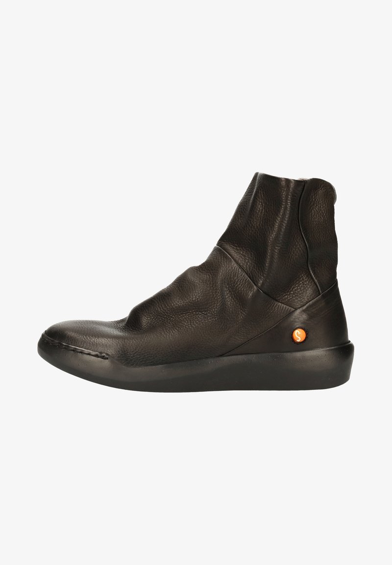 Bottine en cuir noir doux avec un bout arrondi, une semelle plate et un logo circulaire orange près du talon.