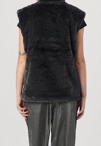 Gray faux fur vest with a high collar and no sleeves, featuring a soft texture and a smooth finish, paired with silver-gray pants.