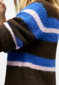 Knitted sweater with brown, blue, and pink stripes. Soft texture, oversized fit, and rounded shoulders. Visible plush fabric detail.
