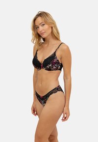 Soutien-gorge en dentelle noire et culotte assortie ornés d'un motif floral coloré, avec un nœud rose sur le soutien-gorge, des bretelles ajustables et une texture lisse.