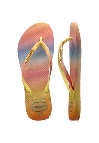 Tongs jaunes avec une semelle dégradée passant du rose au bleu, un footbed texturé et des fines lanières. Présente la marque "Havaianas".